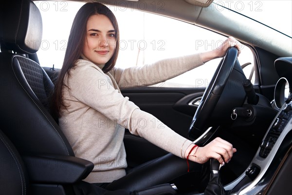 Young beautiful happy woman sitting at the wheel new car