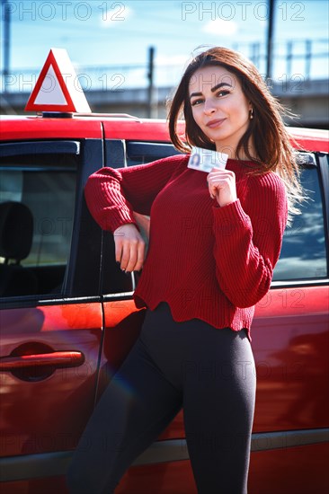 Joyful girl driving a training car with a drivers license card in her hands