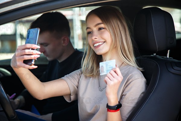 Happy smiling girl takes a selfie with a new drivers license