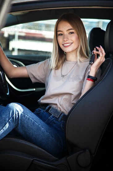 Happy smile girl in a new car with keys in her hand. Lifestyle
