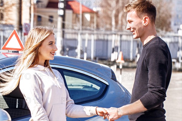 Acquaintance of a driving instructor and a student near a training car. Lesson at the circuit