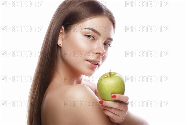 Beautiful young girl with a light natural make-up and perfect skin with apple in her hand. Beauty face. Picture taken in the studio on a white background