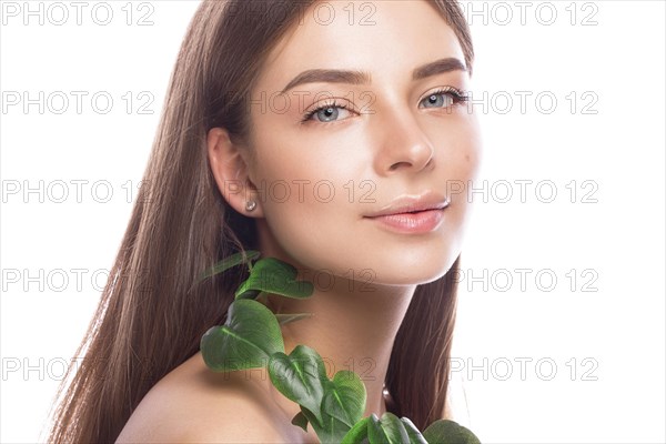 Beautiful young girl with a light natural make-up and perfect skin with Green branch in her hand. Beauty face. Picture taken in the studio on a white background