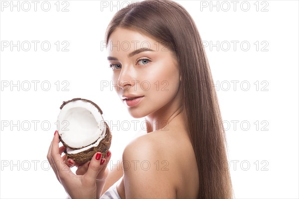 Beautiful young girl with a light natural make-up and perfect skin with coconut in her hand. Beauty face. Picture taken in the studio on a white background