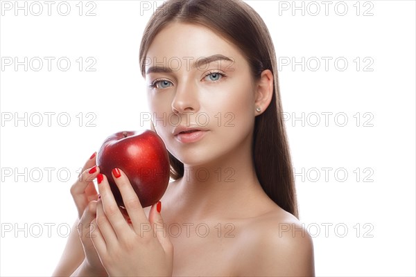 Beautiful young girl with a light natural make-up and perfect skin with apple in her hand. Beauty face. Picture taken in the studio on a white background