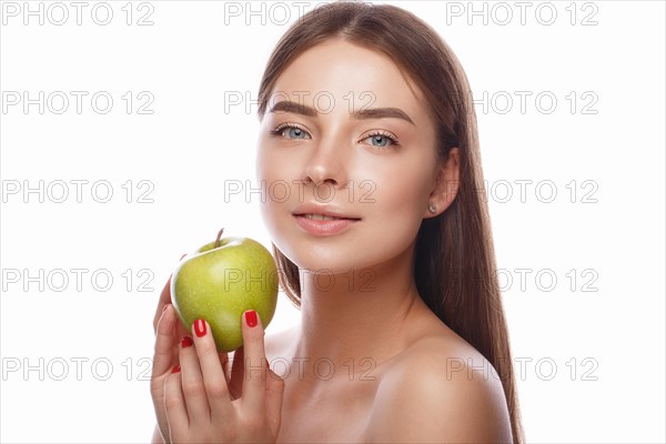 Beautiful young girl with a light natural make-up and perfect skin with apple in her hand. Beauty face. Picture taken in the studio on a white background