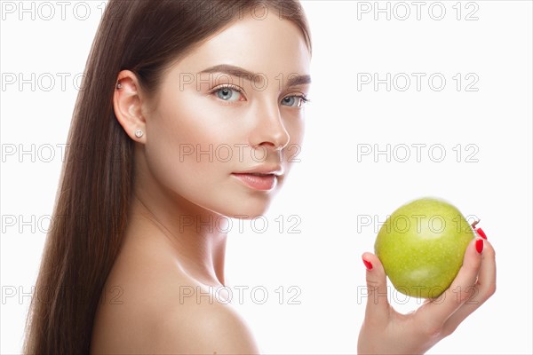 Beautiful young girl with a light natural make-up and perfect skin with apple in her hand. Beauty face. Picture taken in the studio on a white background