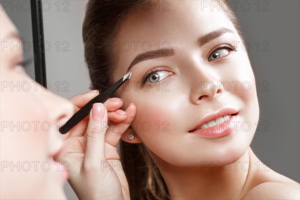 Beautiful girl makes herself a make-up in the mirror. Beauty face. Photo taken in studio
