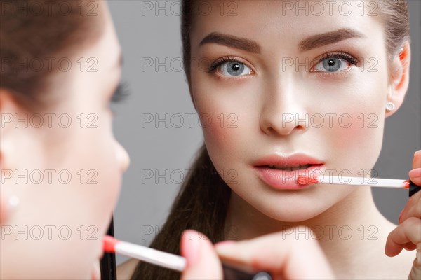 Beautiful girl makes herself a make-up in the mirror. Beauty face. Photo taken in studio