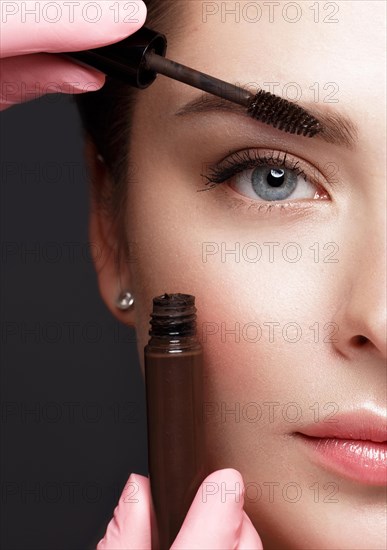 Close-up of female eyes with an eyebrow brush. Eye makeup cosmetics