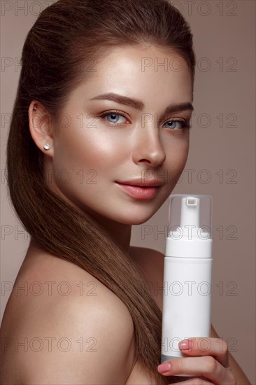 Beautiful young girl with natural nude make-up with cosmetic in hands. Beauty face. Photo taken in studio