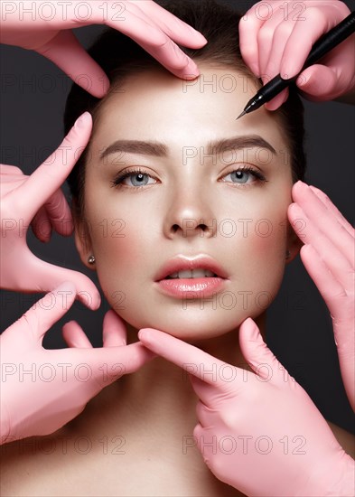Beautiful young girl with natural nude make-up with cosmetic tools in hands. Beauty face. Photo taken in studio