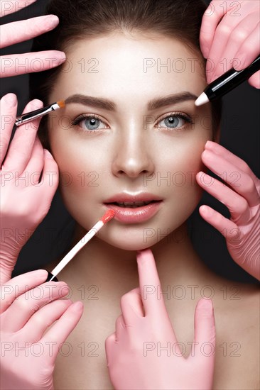 Beautiful young girl with natural nude make-up with cosmetic tools in hands. Beauty face. Photo taken in studio