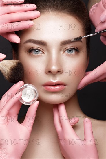 Beautiful young girl with natural nude make-up with cosmetic tools in hands. Beauty face. Photo taken in studio