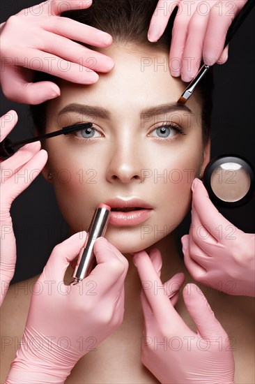 Beautiful young girl with natural nude make-up with cosmetic tools in hands. Beauty face. Photo taken in studio