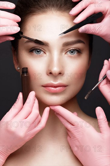 Beautiful young girl with natural nude make-up with cosmetic tools in hands. Beauty face. Photo taken in studio