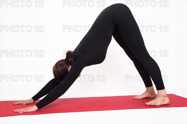 Beautiful athletic girl in a black suit doing yoga. Adho Mukha Svanasana asanas