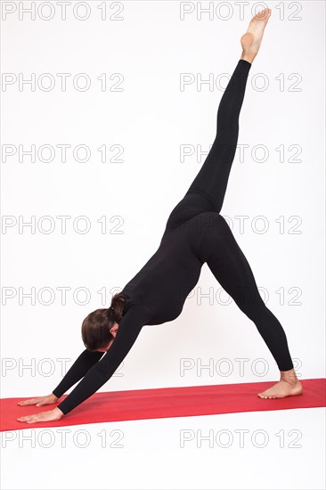 Beautiful athletic girl in a black suit doing yoga. Eka Pada Adho Mukha Svanasana asanas