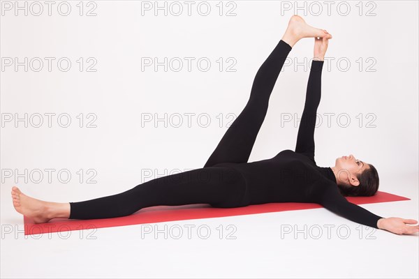 Beautiful athletic girl in black suit doing yoga asanas. Isolated on white background