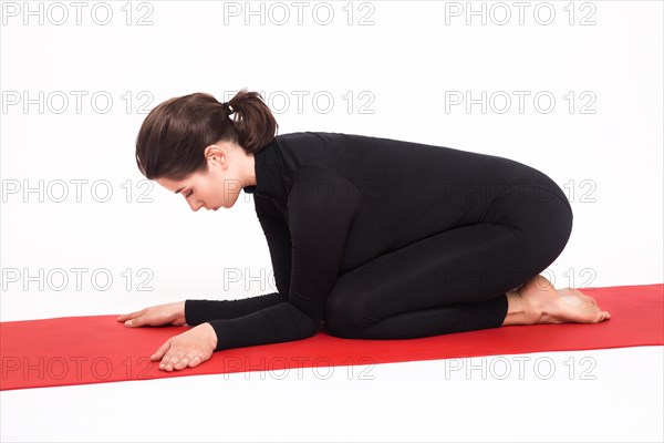 Beautiful athletic girl in a black suit doing yoga. karenukasana asana