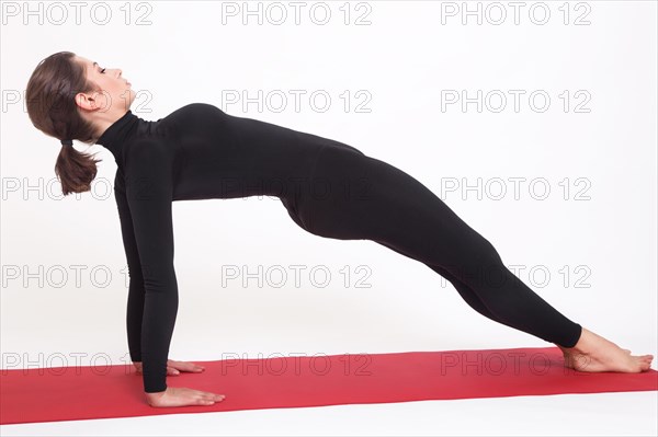 Beautiful athletic girl in black suit doing yoga. Purvottanasana asana plank pose. Isolated on white background