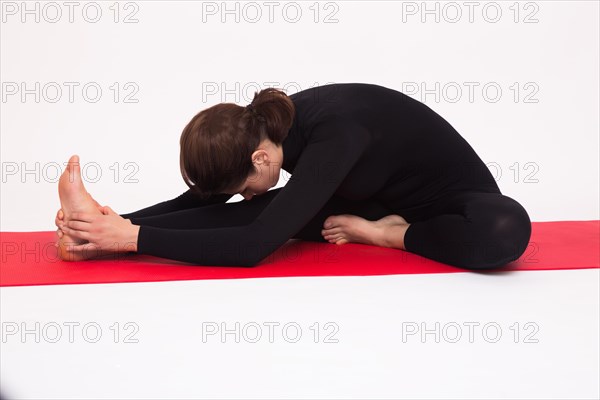 Beautiful athletic girl in black suit doing yoga asanas. Isolated on white background