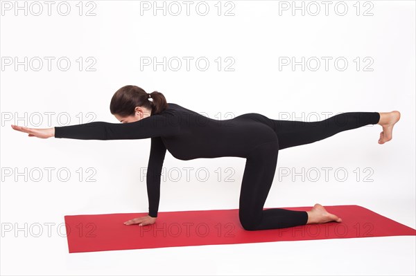 Beautiful athletic girl in a black suit doing yoga. goasana asana