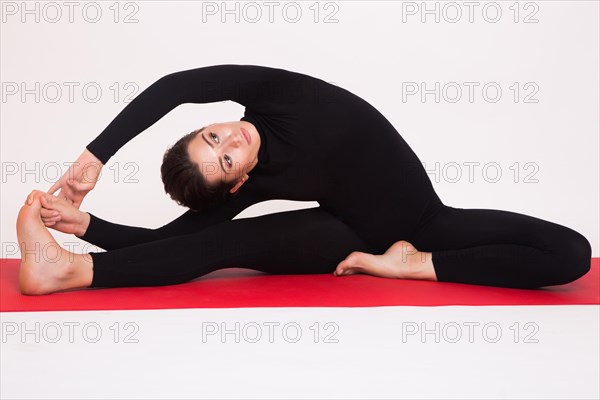 Beautiful athletic girl in black suit doing yoga asanas. Isolated on white background