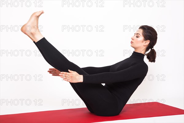 Beautiful athletic girl in a black suit doing yoga. naukasana asana