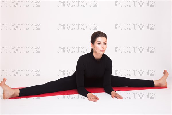 Beautiful athletic girl in black suit doing yoga asanas. Isolated on white background