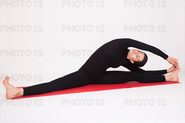 Beautiful athletic girl in black suit doing yoga asanas. Isolated on white background