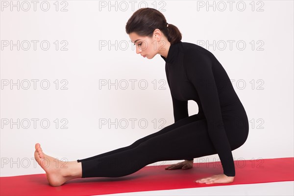 Beautiful athletic girl in black suit doing yoga asanas. Isolated on white background