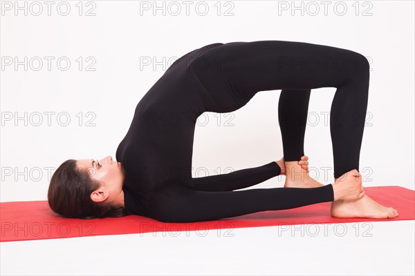 Beautiful athletic girl in a black suit doing yoga. Ardha chakrasana