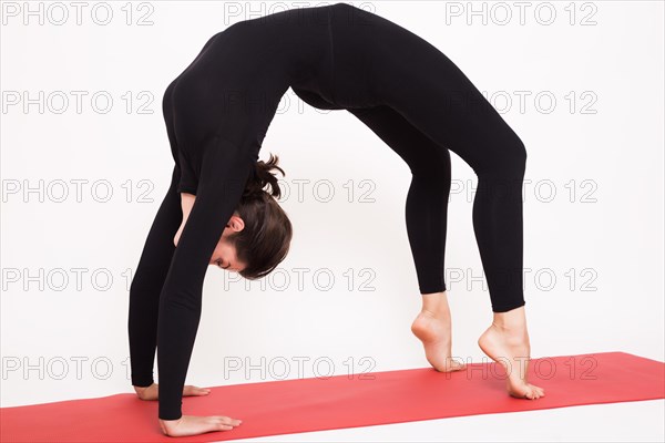 Beautiful athletic girl in a black suit doing yoga. chakrasana