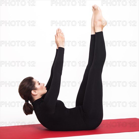 Beautiful athletic girl in a black suit doing yoga. naukasana asana