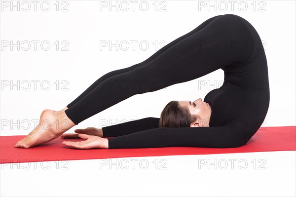 Beautiful athletic girl in a black suit doing yoga. halasana asana