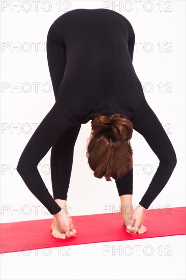 Beautiful athletic girl in black suit doing yoga asanas. Isolated on white background