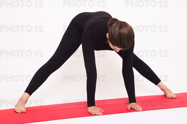 Beautiful athletic girl in black suit doing yoga asanas. Isolated on white background