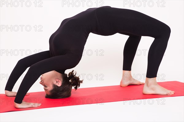 Beautiful athletic girl in black suit doing yoga asanas. Isolated on white background