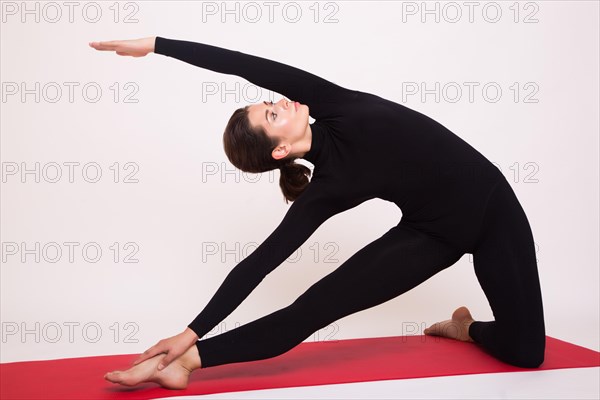 Beautiful athletic girl in black suit doing yoga asanas. Isolated on white background