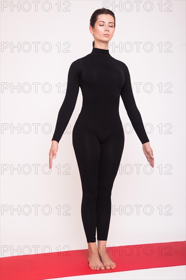 Beautiful athletic girl in black suit doing yoga asanas. Isolated on white background