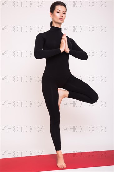 Beautiful athletic girl in black suit doing yoga asanas. Isolated on white background