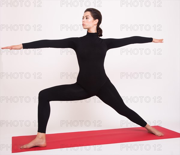 Beautiful athletic girl in black suit doing yoga asanas. Isolated on white background