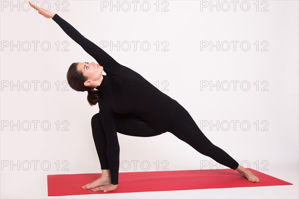 Beautiful athletic girl in black suit doing yoga asanas. Isolated on white background