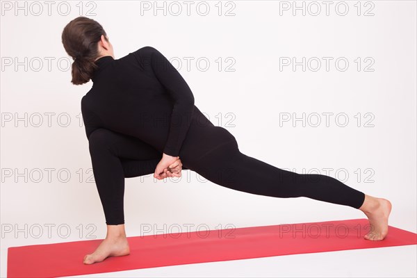 Beautiful athletic girl in black suit doing yoga asanas. Isolated on white background