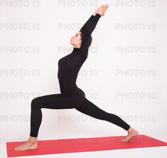 Beautiful athletic girl in black suit doing yoga asanas. Isolated on white background