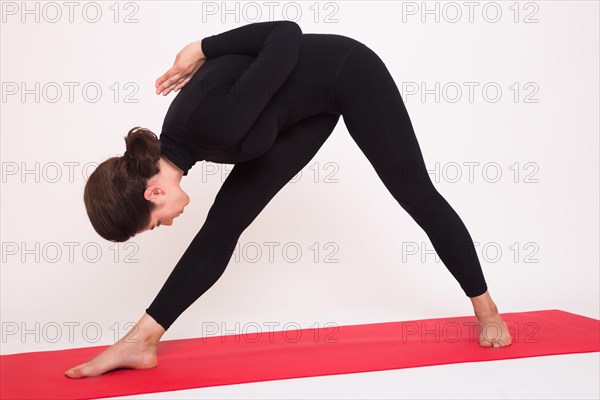 Beautiful athletic girl in black suit doing yoga asanas. Isolated on white background