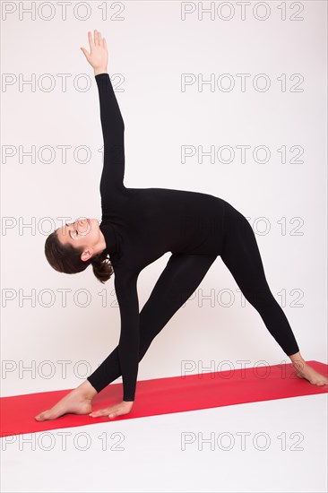 Beautiful athletic girl in black suit doing yoga asanas. Isolated on white background