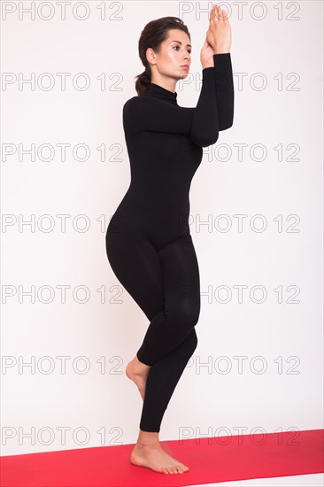 Beautiful athletic girl in black suit doing yoga asanas. Isolated on white background