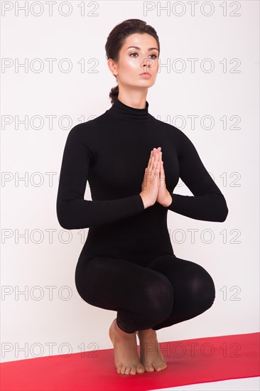 Beautiful athletic girl in black suit doing yoga asanas. Isolated on white background